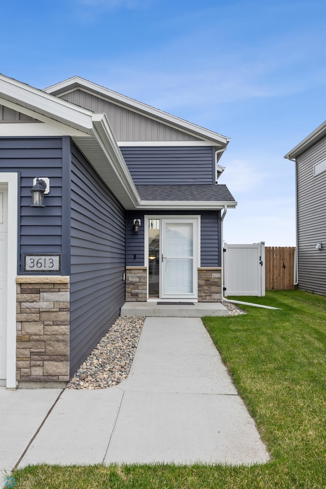 doorway to property featuring stone siding, board and batten siding, and a shingled roof