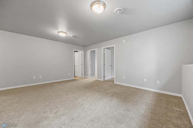 carpeted spare room with baseboards and a smoke detector
