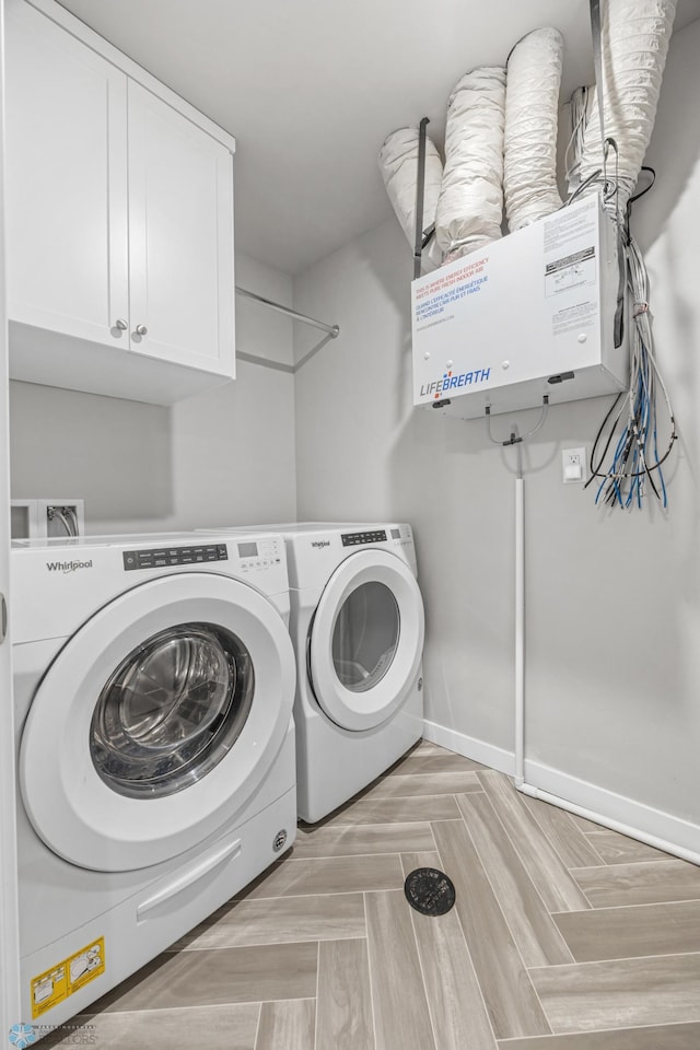 laundry room with separate washer and dryer, cabinet space, and baseboards