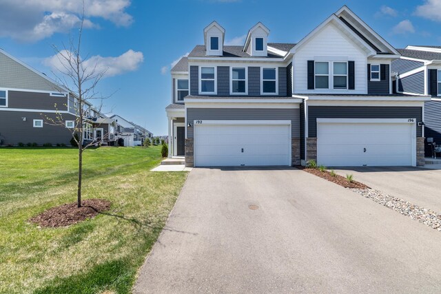 192 Junco Rd N, Lake Elmo, MN 55042 - view of front of house featuring an attached garage, driveway, a front yard, and stone siding