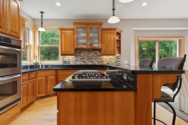 1376 Cobblestone Rd N, Champlin, MN 55316 - kitchen with appliances with stainless steel finishes, light wood finished floors, a breakfast bar area, recessed lighting, and decorative backsplash