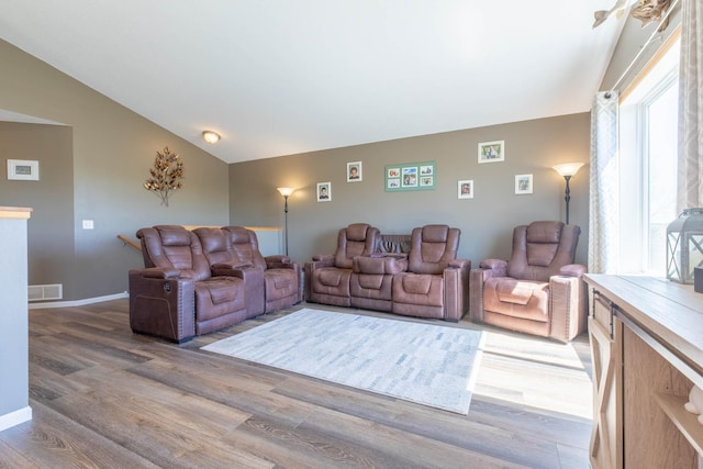 living room with light wood-style flooring, lofted ceiling, and baseboards
