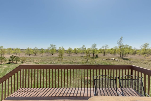 wooden terrace with a lawn and a view of countryside