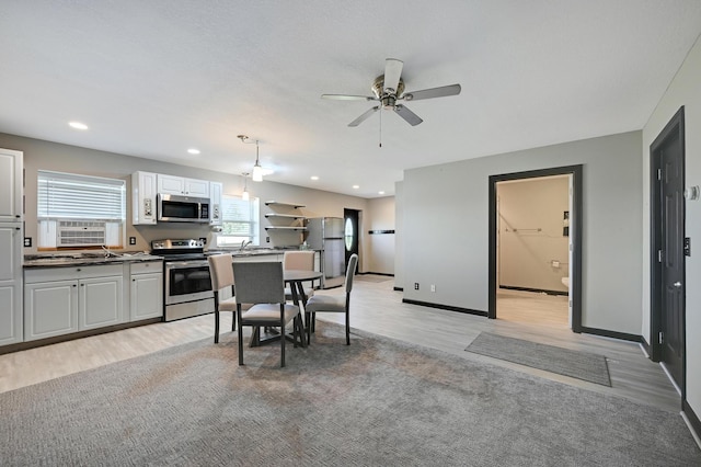 14590 Thicket Ln, Dayton, MN 55327 - kitchen featuring appliances with stainless steel finishes, light wood-style flooring, a ceiling fan, white cabinetry, and dark countertops