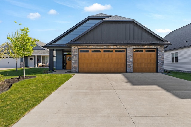 craftsman house featuring a front yard, board and batten siding, an attached garage, stone siding, and concrete driveway