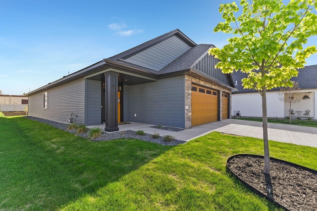 view of front of house with concrete driveway, board and batten siding, an attached garage, stone siding, and a front lawn