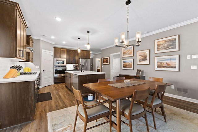 dining space featuring ornamental molding, dark wood-style flooring, recessed lighting, a chandelier, and baseboards