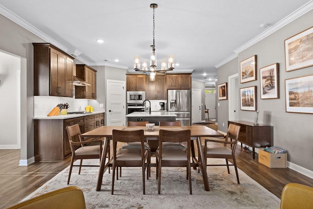 kitchen featuring stainless steel appliances, a kitchen island with sink, dark wood-type flooring, baseboards, and a chandelier
