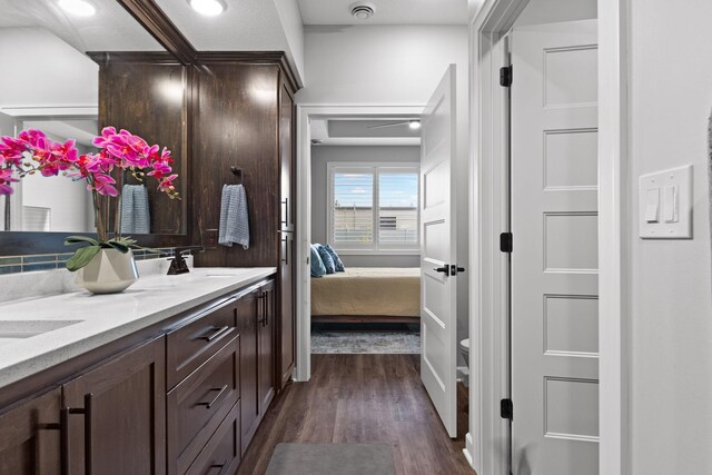 ensuite bathroom featuring wood finished floors, toilet, and double vanity