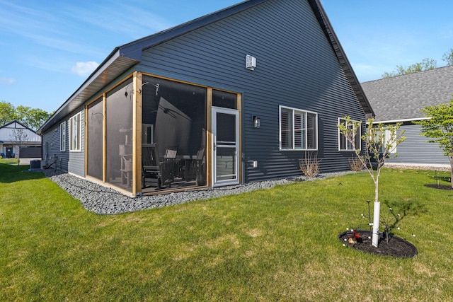 rear view of house featuring a sunroom, a yard, and central AC