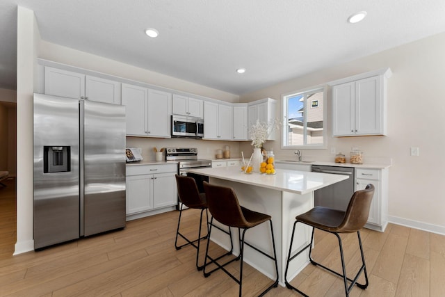 7478 170th Ave NW, Ramsey, MN 55303 - kitchen featuring stainless steel appliances, a breakfast bar, light wood finished floors, light countertops, and recessed lighting