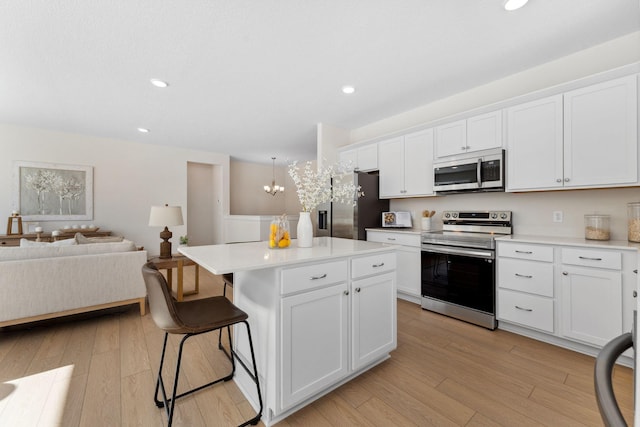 7478 170th Ave NW, Ramsey, MN 55303 - kitchen featuring stainless steel appliances, a kitchen breakfast bar, white cabinets, light wood-style flooring, and open floor plan