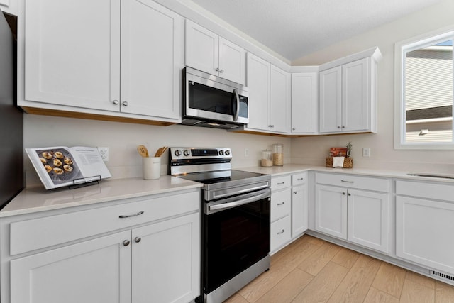 7478 170th Ave NW, Ramsey, MN 55303 - kitchen with stainless steel appliances, light wood-style floors, light countertops, and white cabinetry