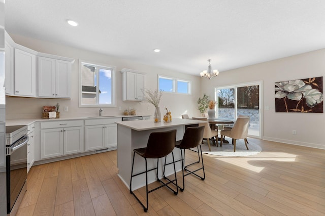 7478 170th Ave NW, Ramsey, MN 55303 - kitchen with a chandelier, stainless steel range with electric stovetop, light countertops, a kitchen island, and a breakfast bar