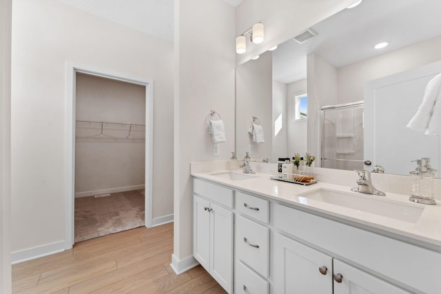 7478 170th Ave NW, Ramsey, MN 55303 - full bathroom featuring a stall shower, wood finished floors, double vanity, a spacious closet, and baseboards