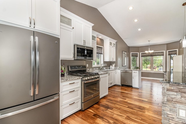 1270 145th Ave NW, Andover, MN 55304 - kitchen with appliances with stainless steel finishes, vaulted ceiling, a peninsula, light wood-style floors, and white cabinets