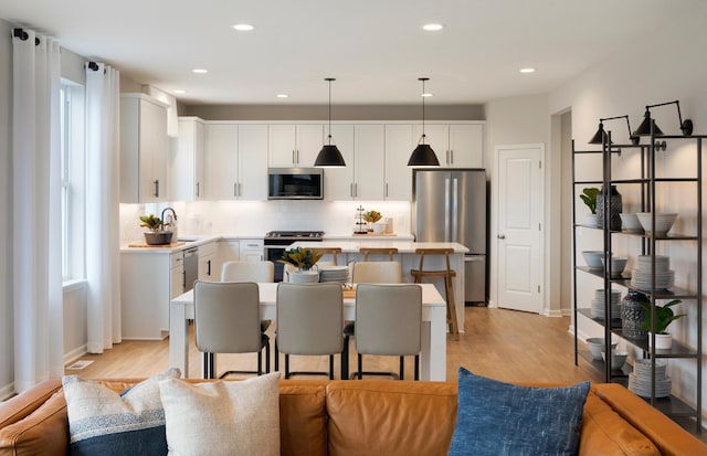 19600 104th Pl, Corcoran, MN 55374 - kitchen featuring stainless steel appliances, open floor plan, a center island, decorative backsplash, and light wood-style floors