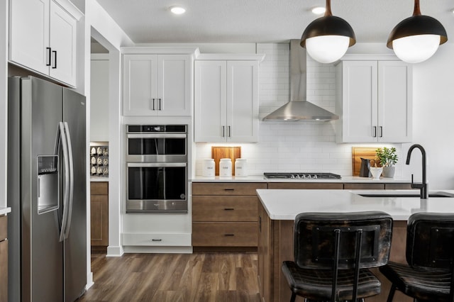 19649 105th Ave, Corcoran, MN 55374 - kitchen with stainless steel appliances, wall chimney exhaust hood, a sink, light countertops, and dark wood-style floors