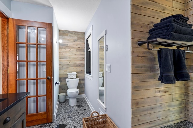 8132 Fillmore St NE, Spring Lake Park, MN 55432 - bathroom with toilet, baseboards, wooden walls, and french doors