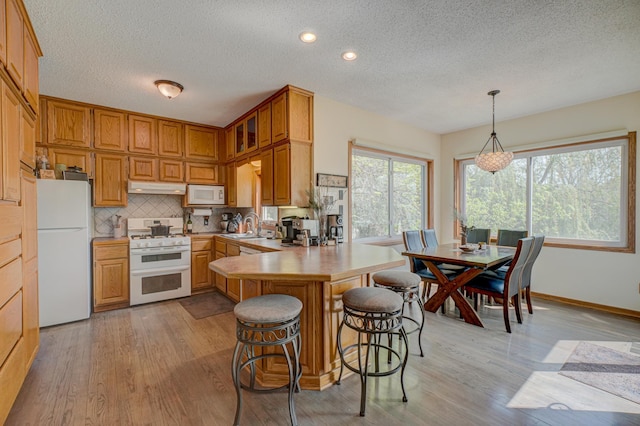 2167 Woodbridge Way, Woodbury, MN 55125 - kitchen with white appliances, under cabinet range hood, a textured ceiling, a peninsula, and a sink