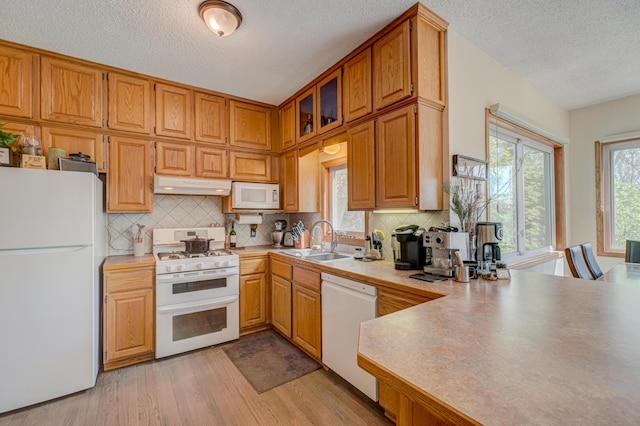 2167 Woodbridge Way, Woodbury, MN 55125 - kitchen with white appliances, under cabinet range hood, a sink, a textured ceiling, and light wood-type flooring