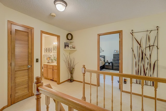 2167 Woodbridge Way, Woodbury, MN 55125 - hall featuring light carpet, a textured ceiling, an upstairs landing, and baseboards