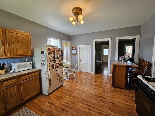 kitchen with white appliances, dark wood-style flooring, brown cabinetry, and light countertops