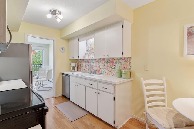 kitchen featuring a sink, appliances with stainless steel finishes, light wood-style flooring, and white cabinetry