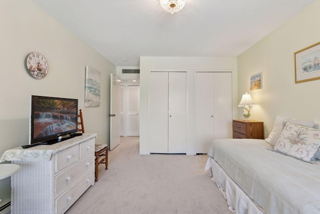 bedroom with light carpet, multiple closets, and baseboard heating