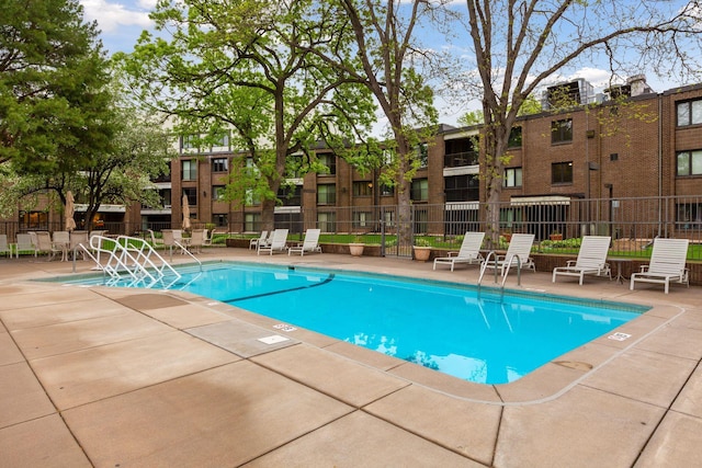 community pool with fence and a patio area