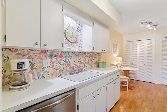 kitchen featuring a sink, dishwasher, light countertops, and white cabinetry