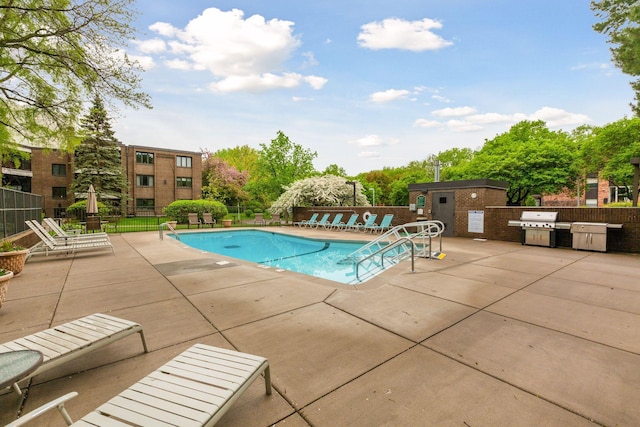 community pool featuring a patio, fence, area for grilling, and an outbuilding