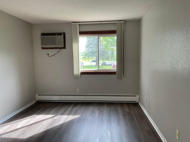 3440 Golfview Dr Unit 123, Eagan, MN 55123 - empty room with an AC wall unit, a baseboard radiator, dark wood-type flooring, a textured ceiling, and baseboards
