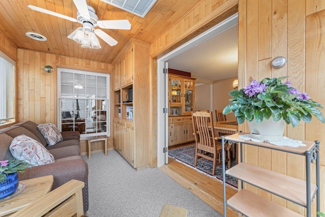 living room featuring wood walls, ceiling fan, light colored carpet, and wooden ceiling