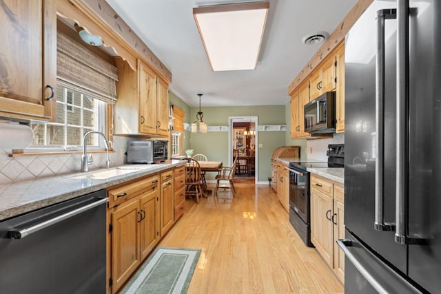kitchen with freestanding refrigerator, black range with electric stovetop, dishwashing machine, a sink, and light wood-style flooring