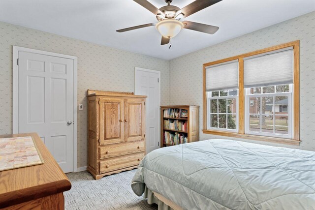 bedroom with light colored carpet, wallpapered walls, and a ceiling fan