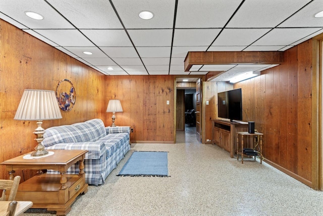 living area with baseboards, wooden walls, a paneled ceiling, and recessed lighting