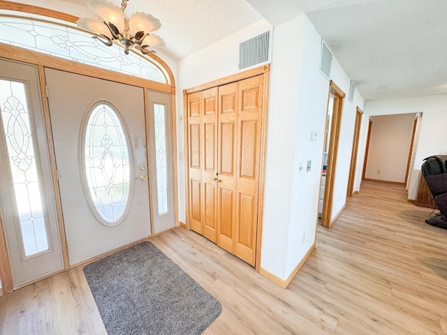 49262 Big Pine Rd, Perham, MN 56573 - foyer featuring a chandelier, light wood-style floors, a textured ceiling, and baseboards