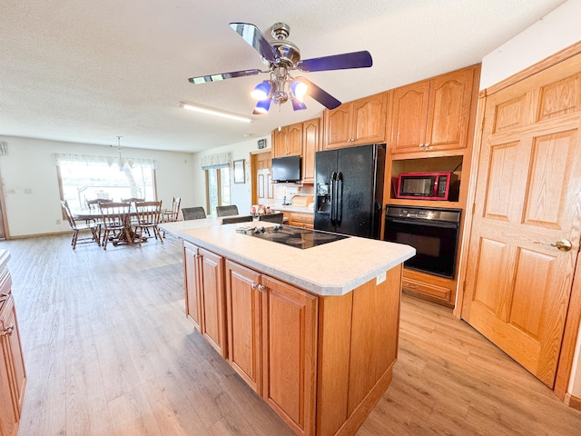 49262 Big Pine Rd, Perham, MN 56573 - kitchen featuring black appliances, light wood finished floors, a center island, light countertops, and ceiling fan