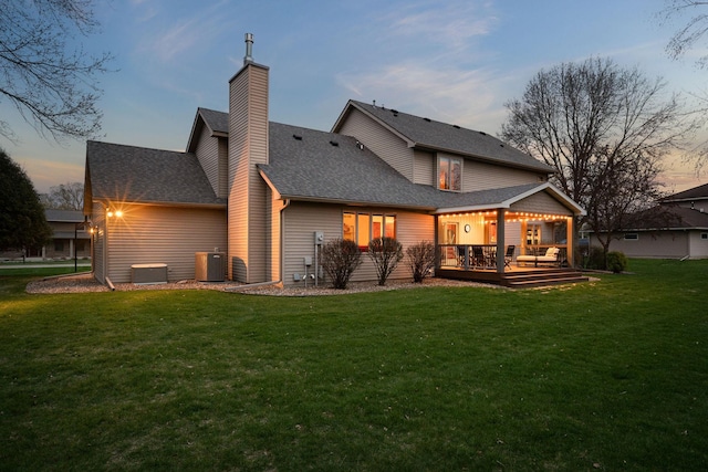 rear view of property featuring cooling unit, a lawn, a wooden deck, and a chimney