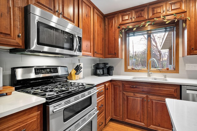 kitchen with appliances with stainless steel finishes, a sink, brown cabinets, and decorative backsplash