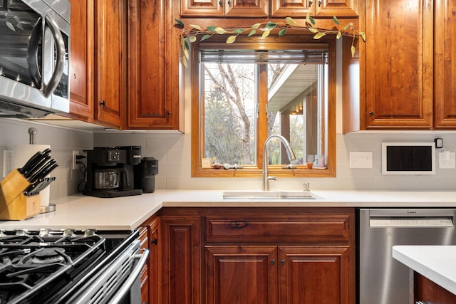 kitchen with appliances with stainless steel finishes, a sink, decorative backsplash, and light countertops
