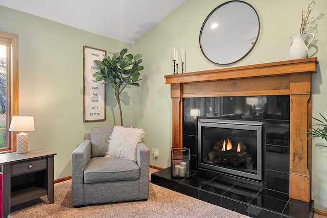 living area featuring a tiled fireplace, carpet floors, and baseboards