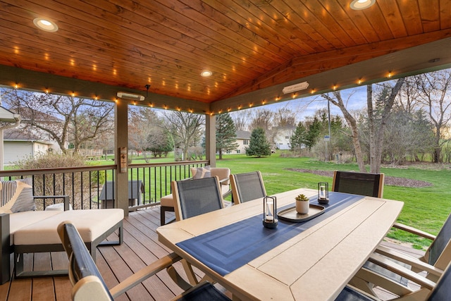 wooden terrace with outdoor dining area and a lawn