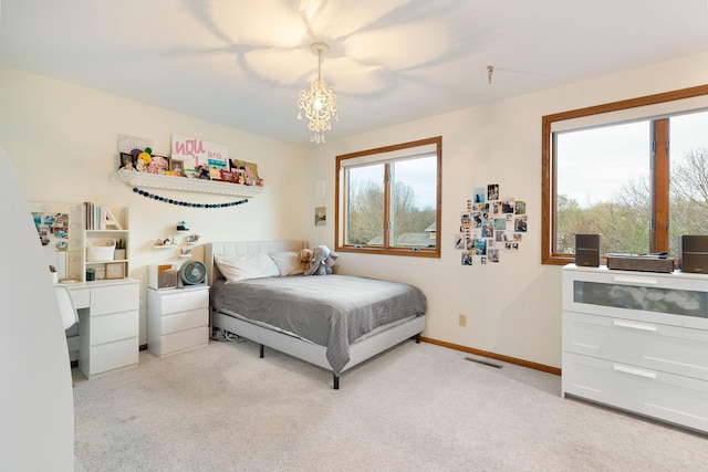 bedroom featuring light colored carpet, baseboards, and a chandelier