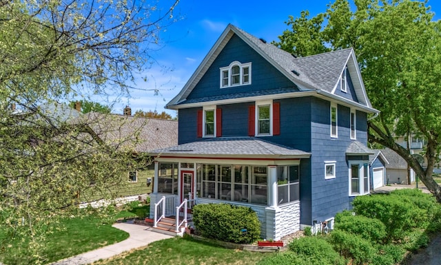rear view of property featuring roof with shingles, a sunroom, a lawn, and a garage