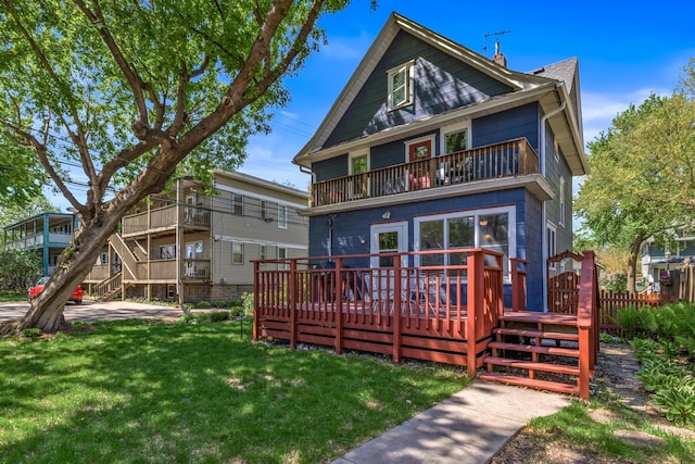 back of property with a balcony, a yard, and a deck