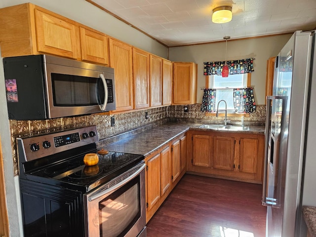 kitchen with appliances with stainless steel finishes, a sink, dark wood-style floors, decorative backsplash, and dark countertops