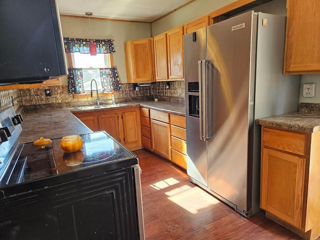 kitchen with electric range, stainless steel fridge, a sink, wood finished floors, and backsplash