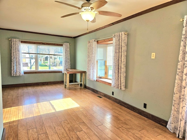 spare room featuring ornamental molding, ceiling fan, wood finished floors, and baseboards
